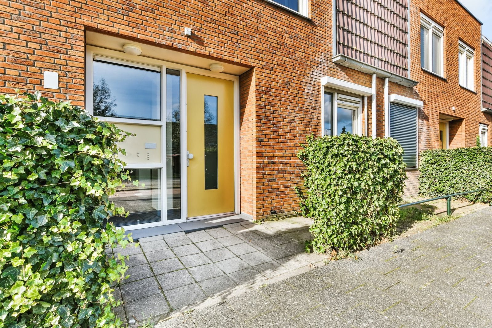 Front door with yellow door and greenery